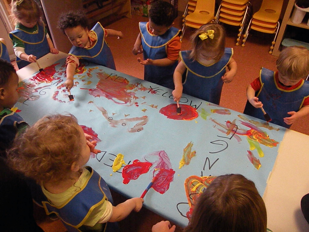Toddlers mixing paint to make orange