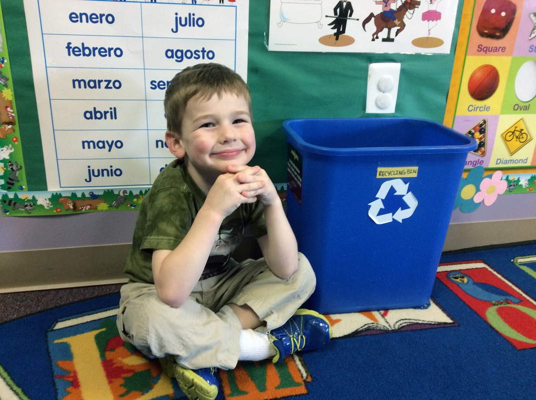 Pre-School student smiling with recycling bin